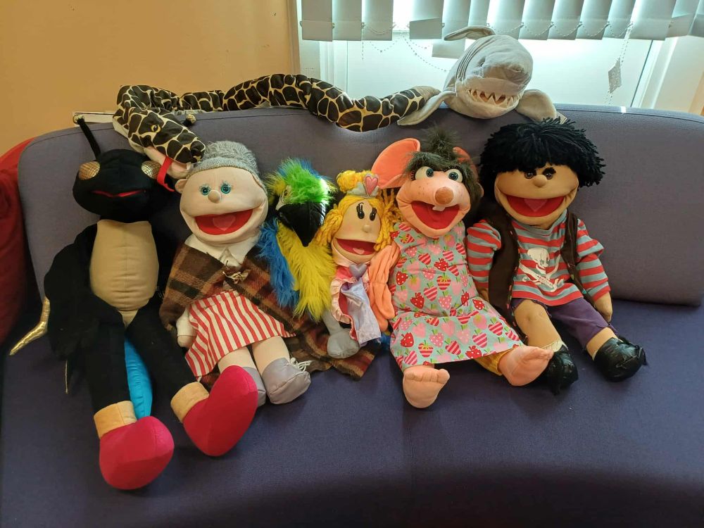 some brightly coloured hand puppets sit on a sofa
