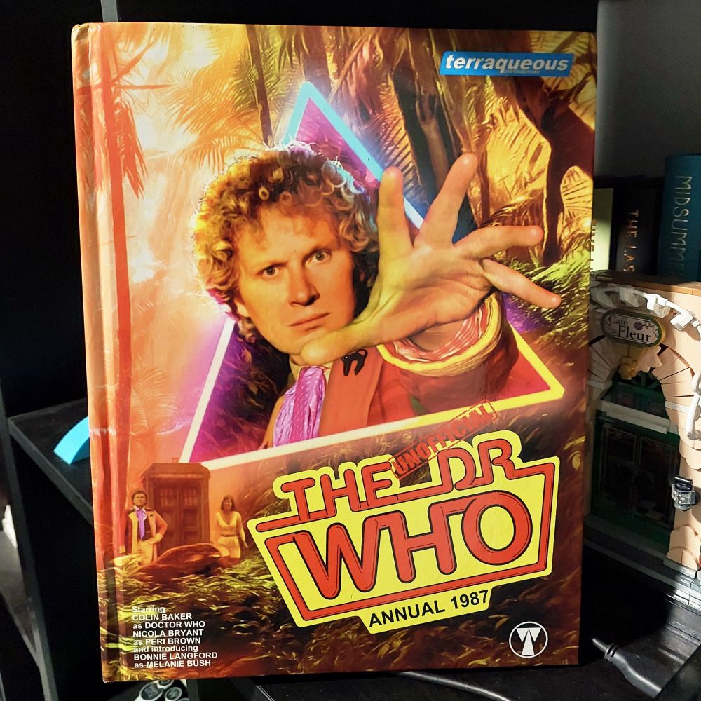 A hardcover Unofficial Doctor Who Annual 1987, by Terraqueous, featuring Colin Baker as the Sixth Doctor on the cover, reaching out to the reader.