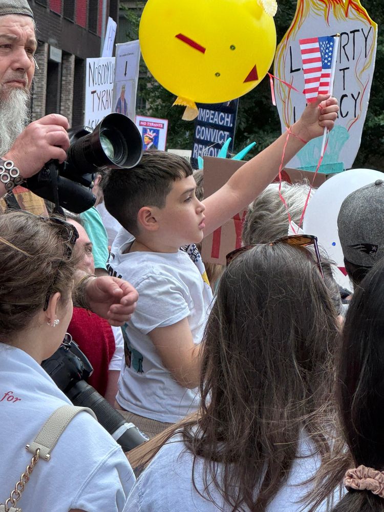 Young boy, amidst a crowd, holding up an American flag