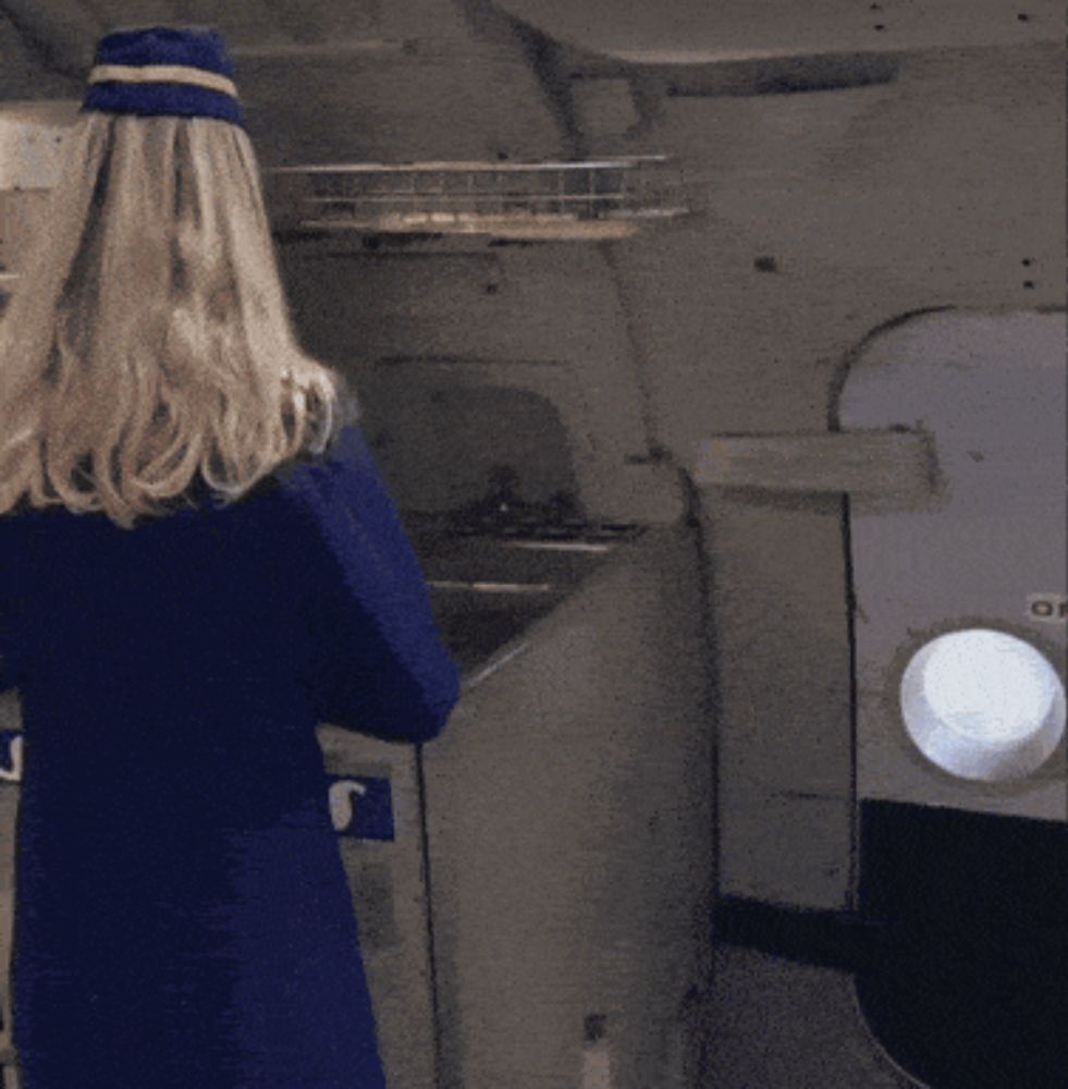 a woman in a blue coat and hat is standing in front of a machine with the letter j on it