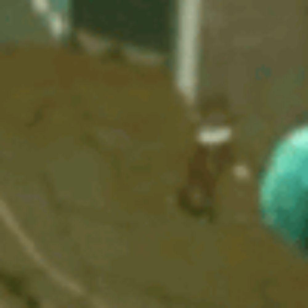 a green balloon is floating in the air on a brown floor .