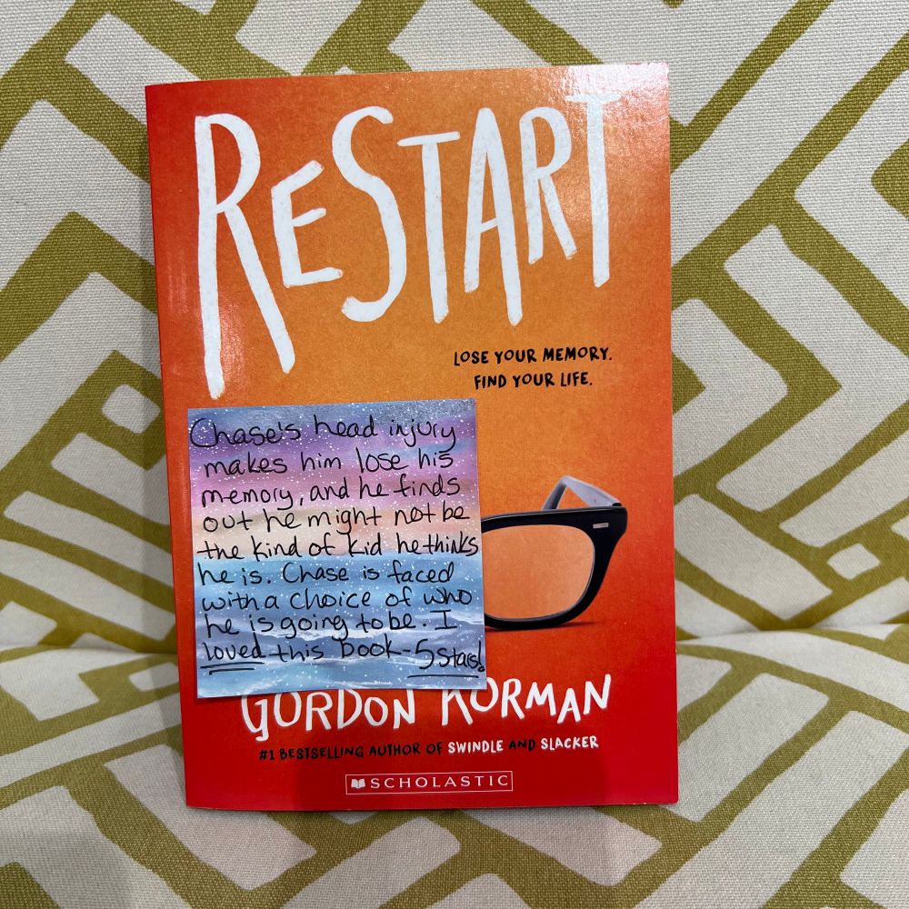 A picture of the book Restart by Gordon Korman, with a sticky note attached to the cover. The next picture shows what the sticky note says.