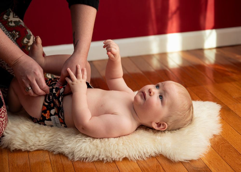 A mom changing her baby's diaper while he looks up at her. 