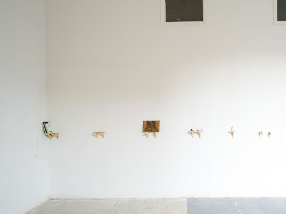 Small artworks on the wall. A display made of play dough is holding each artwork.