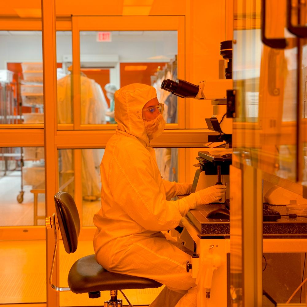 Sarah Odinotski working inside of the Cleanroom wearing scrubs and a mask