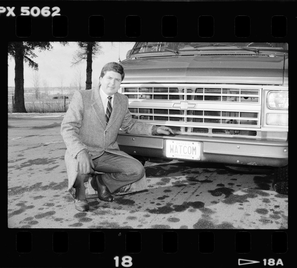 Dr. Don Cowan standing by a van with a license plate that says WATCOM