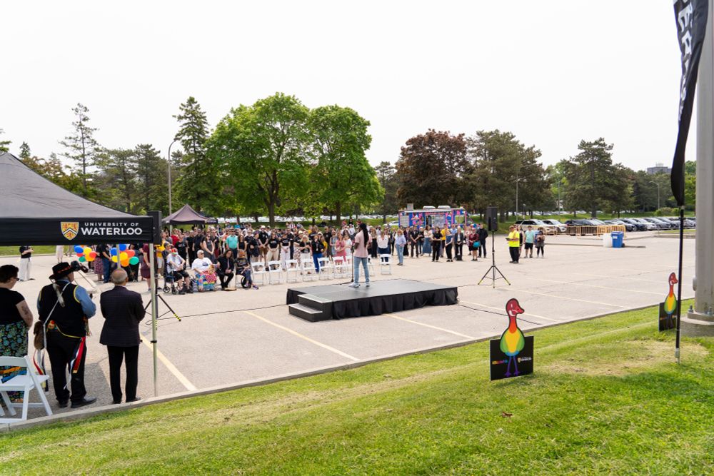A large crowd gathering for the re-raising of the Intersex-Inclusive Progress flag and the Two-Spirit Pride flag in celebration of Pride at Waterloo