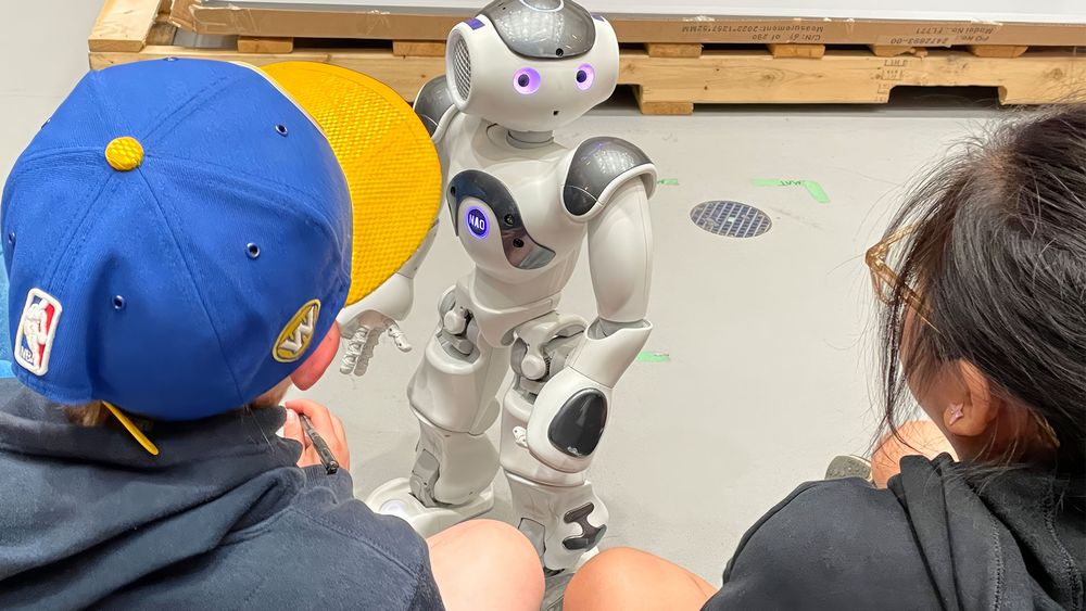 Kids looking on at a robot inside of the robohub at UWaterloo