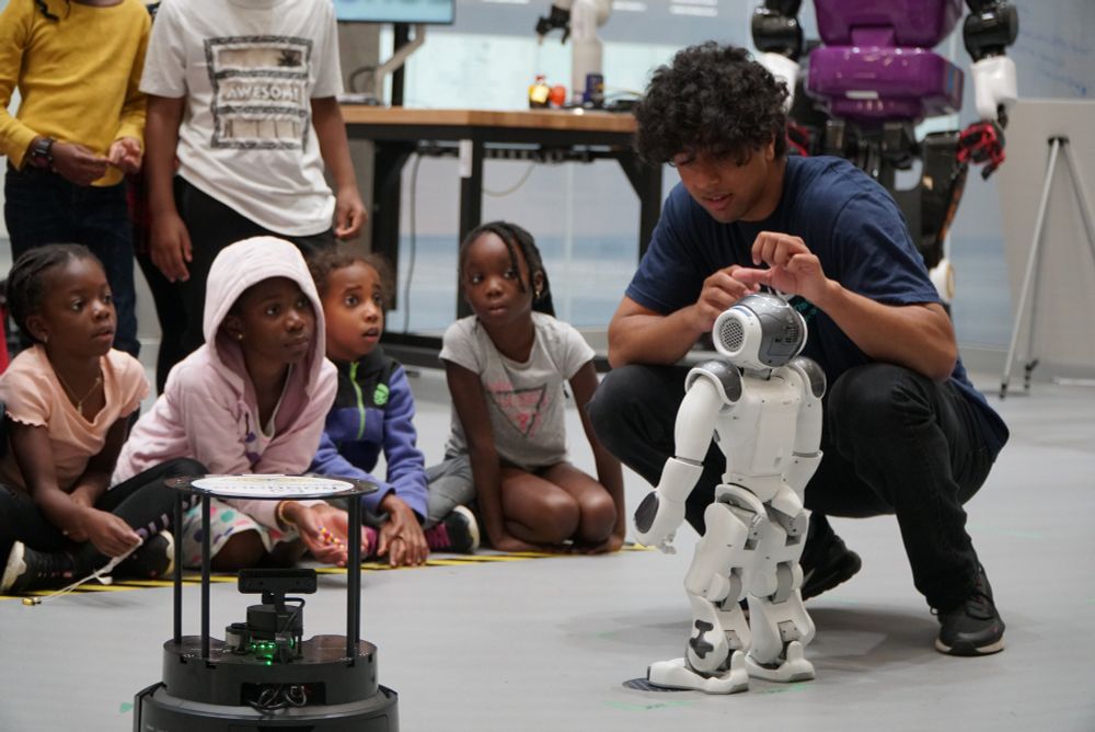 A UWaterloo student showing off how a robot works to onlooking kids during an Engineering Outreach program