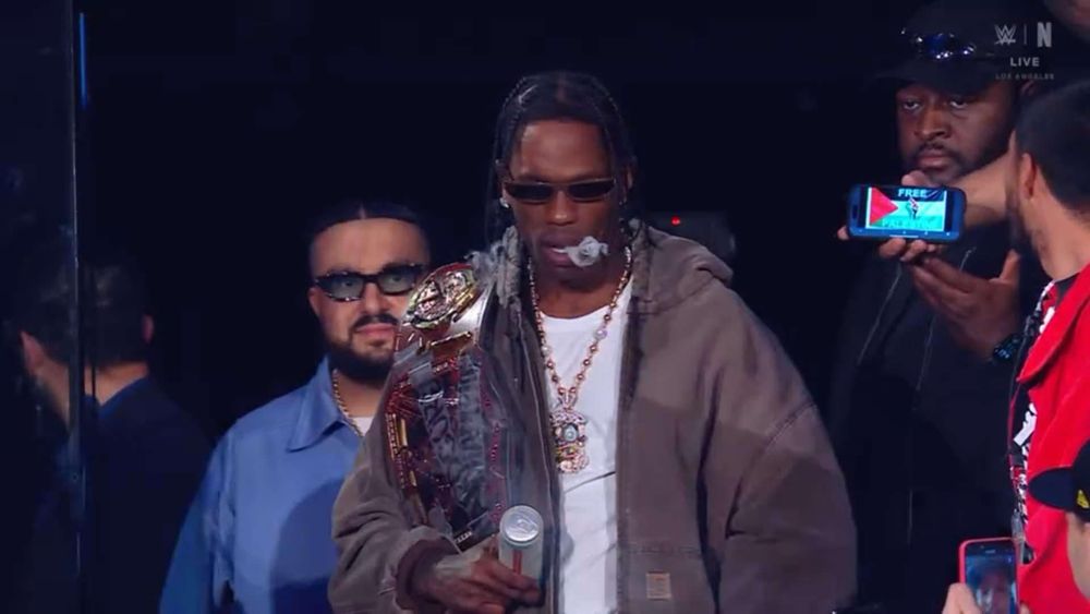 Travis Scott in the crowd at WWE Raw with a phone next to him showing a Palestinian flag and “Free Palestine” on it