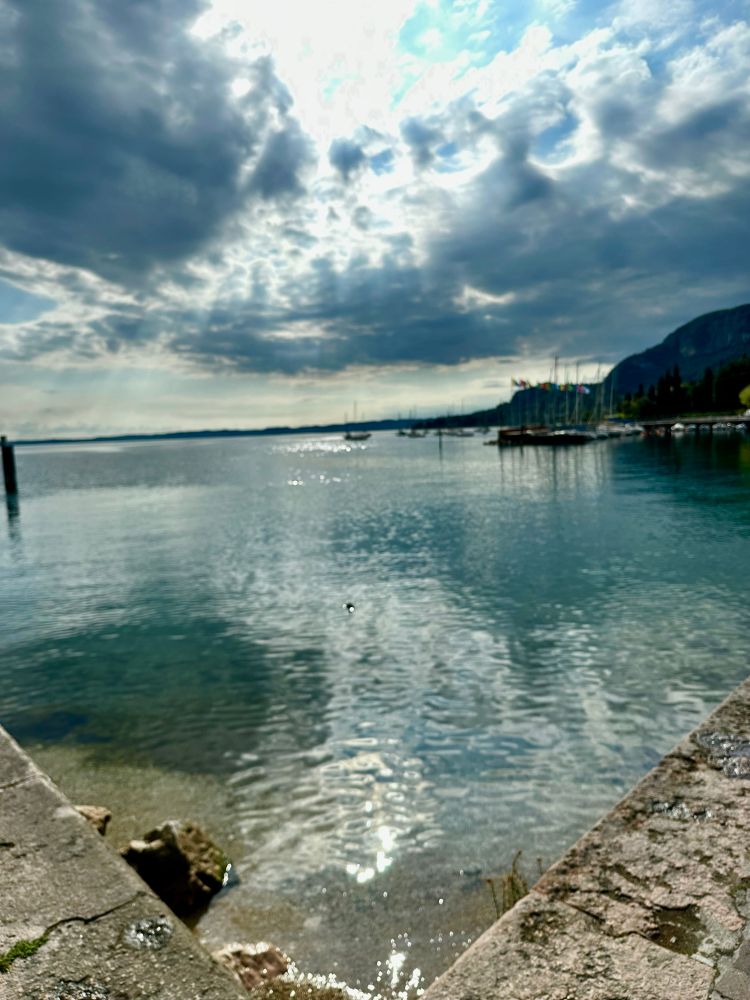The tranquil green waters of Lake Garda shine under an ominous cloud. 