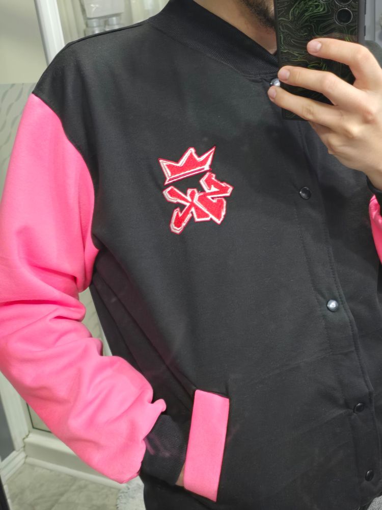 Picture of me wearing a pink and black varsity jacket with a patch on the left side with the initials "SK" with a crown on top 