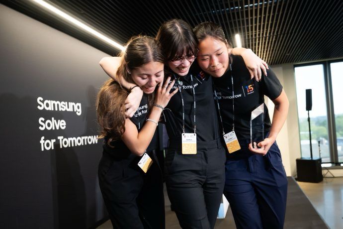 Three very happy young women clutch each other and an award from Samsung Solve for Tomorrow 