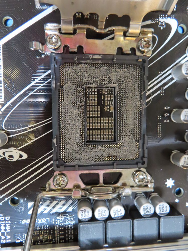 Photo gros plan du socket d'une carte mère en socket Intel 1700. Les 1700 broches sont recouvertes d'une épaisse couche de pâte thermique, rendant le composant définitivement inutilisable... 