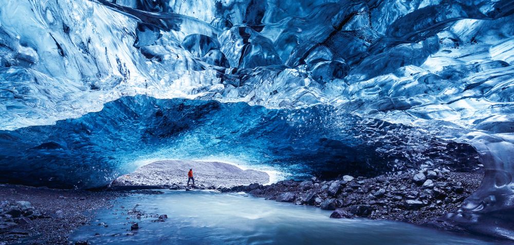 Ice cave at Jokulsarlon glacier in Iceland. A man can be seen in the distance at the mouth of the cave.