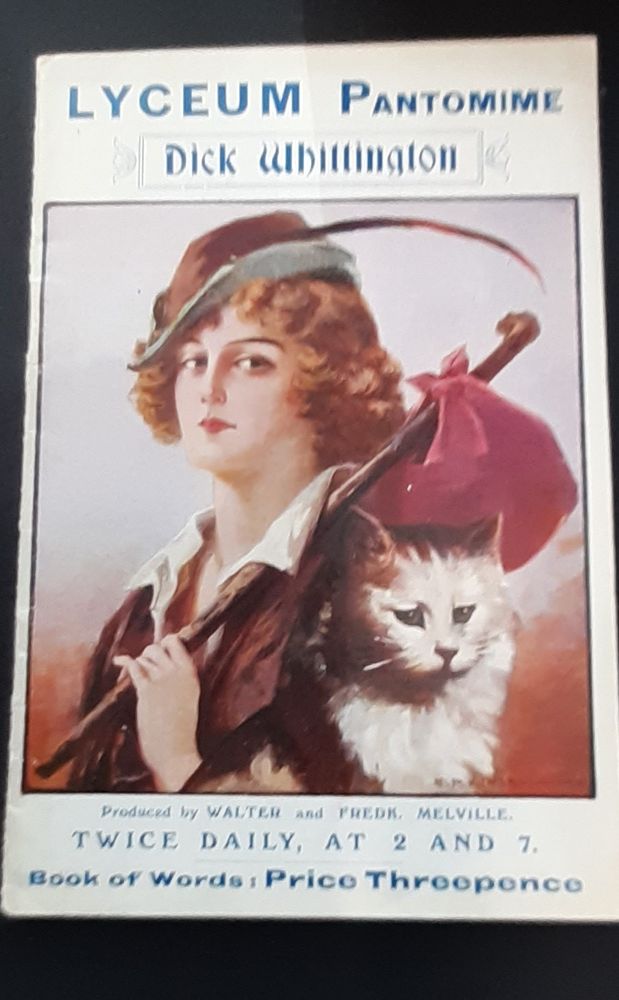 ‘Dick Whittington and his cat: book of words’. London: Lyceum Theatre, 1919. Colour illustration shows Whittington in cap with feather, carrying belongings in a red bundle on a stick over left shoulder. A long-haired cat sits to the right.
