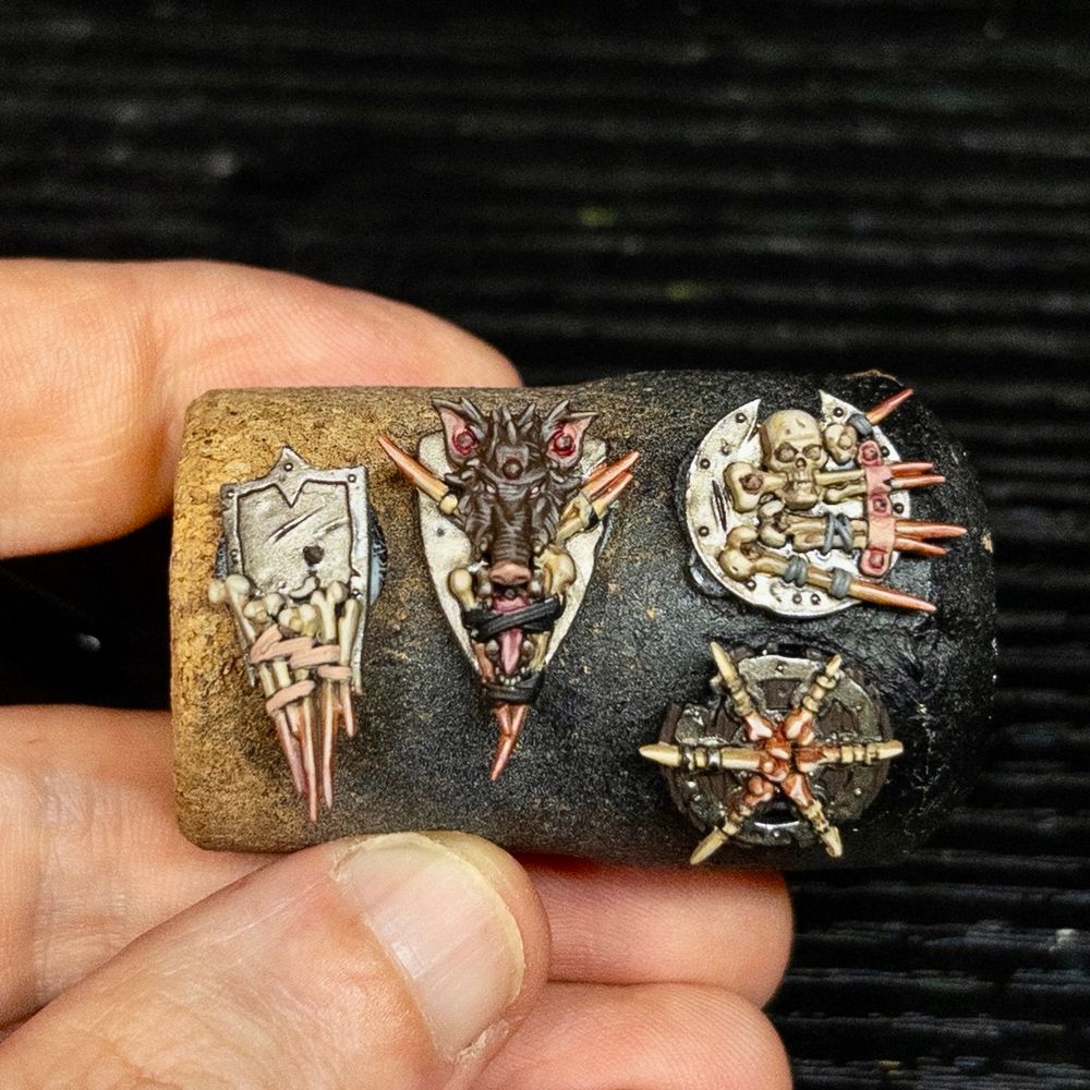 four small warhammer dirty metal shields with with bone and skin replacing heraldry 