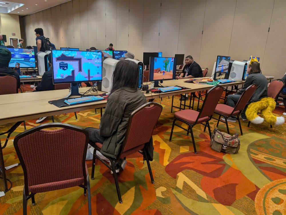 Two individuals playing Soda Powered Penguin and Sonic Rush 3D, while a screenshot of Bun 'N' Gun is displayed in-between them.