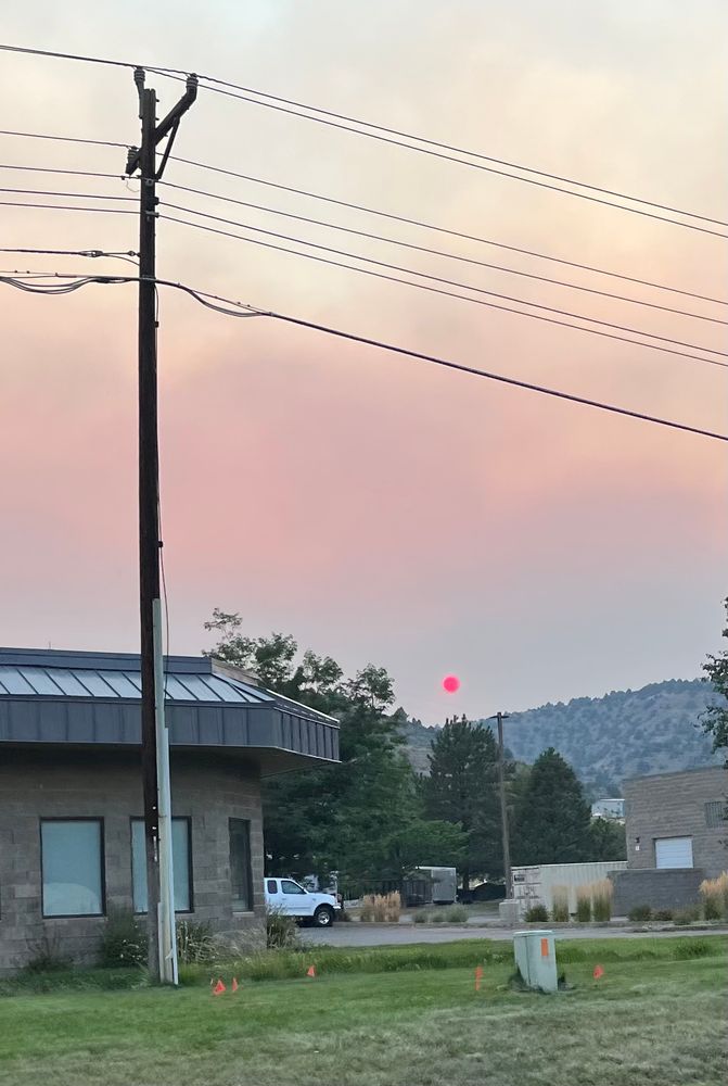 Bright red dot of a sun low in the horizon, reddened by wildfire smoke