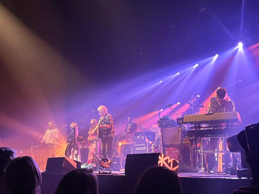 A live stage with blue and burgandy lights illuminating musicians poised to make art