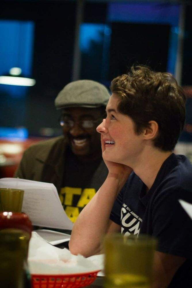 a young woman with short dark hair looking up and laughing in a cafe 