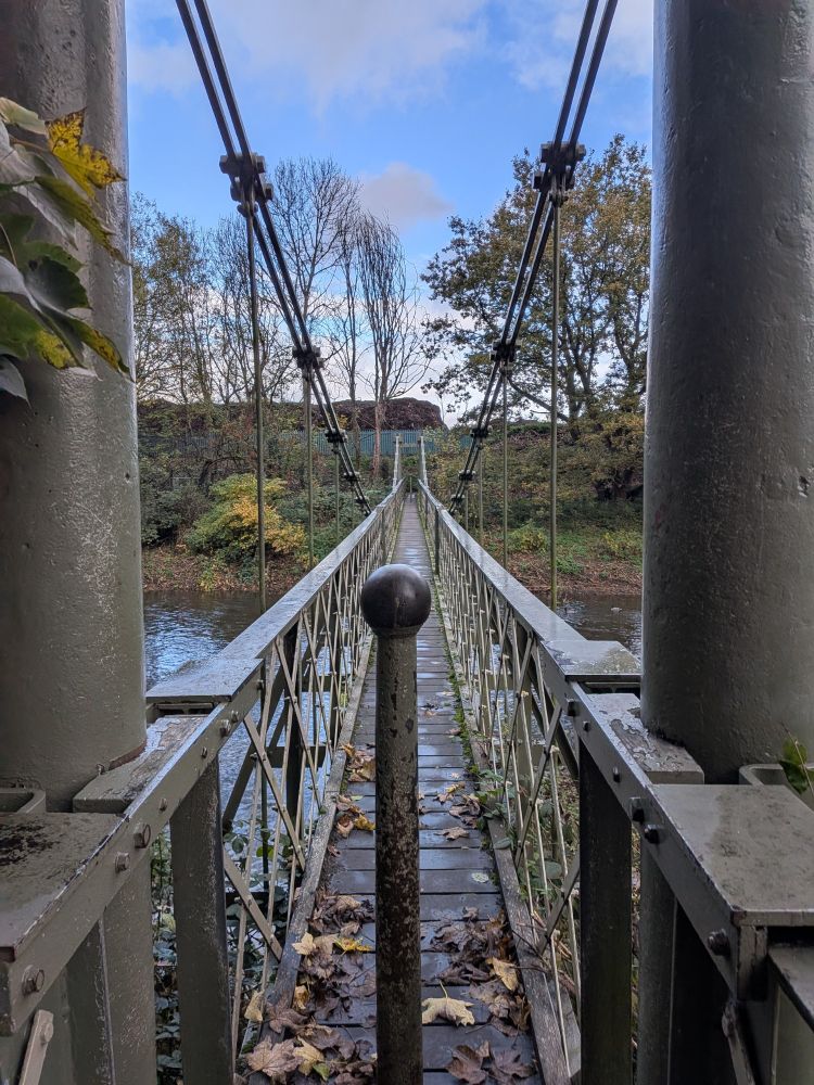 A narrow metal footbridge across the River Aire