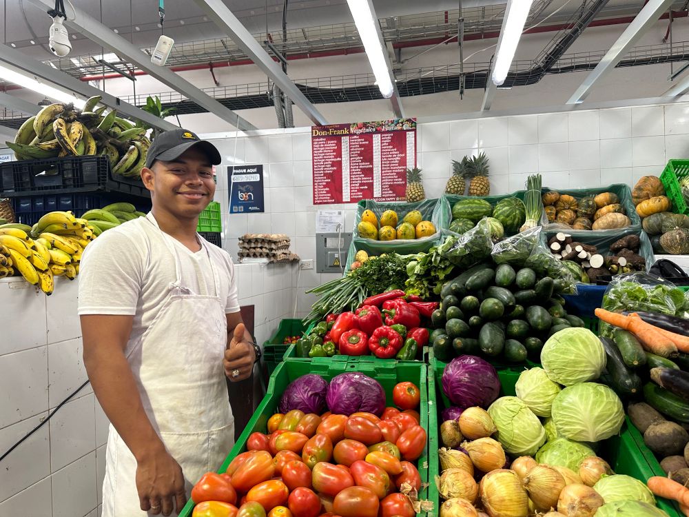 Smiling vendor stands proudly next to his stand of beautiful produce. A crate of tomatoes, one of onions and cabbage. Peppers and cucumbers peek out from behind. Market shopping is one of the joys of cruising life. 