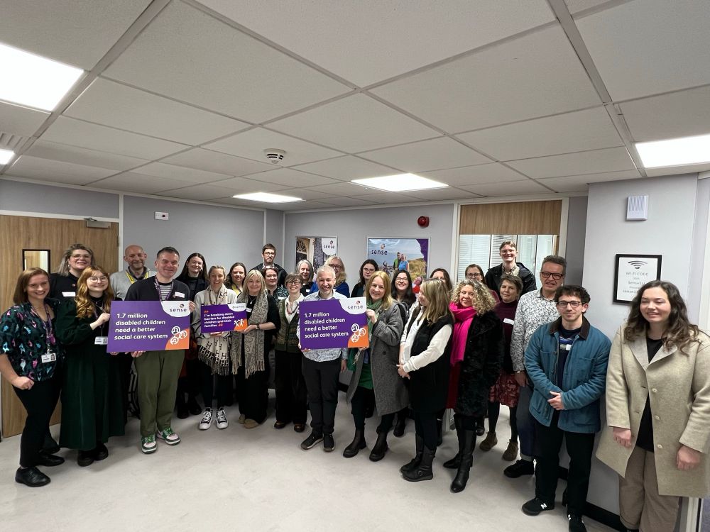 A photo of around 20 people holding three Sense-branded placards that say “1.7 million disabled children need better social care laws.” Representatives in the picture are from disabled children’s charities and service providers from across the country who are fighting for a more equal world for disabled children.