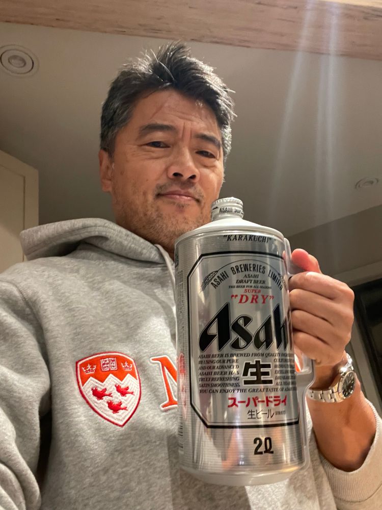A middle aged Korean man holds a 2 quart can of Asahi beer. 