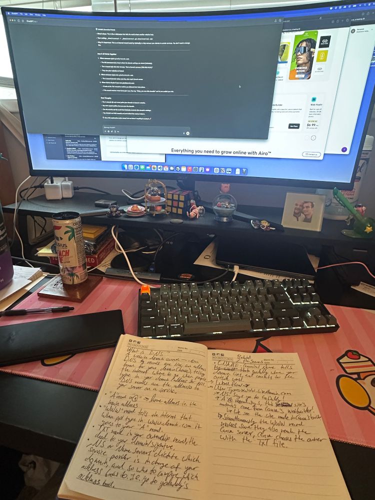 Photo of a computer desk with a screen monitor and notebook with notes. Cute characters are on the desk as well. 