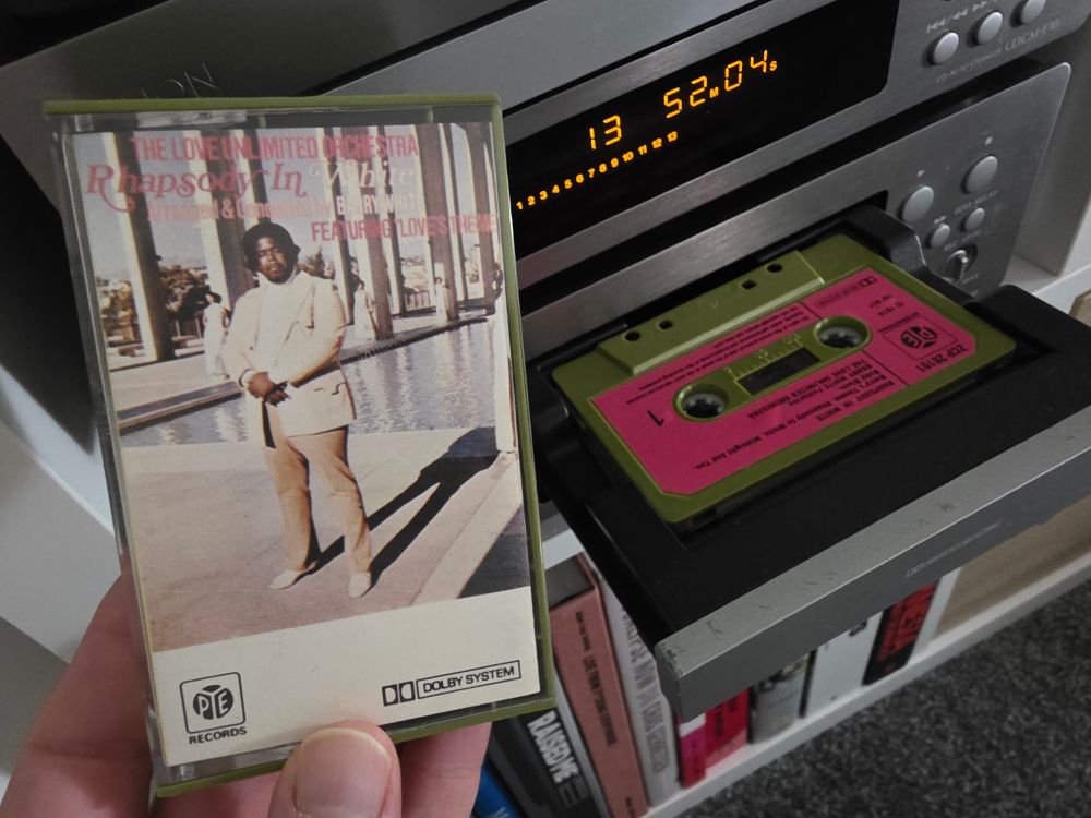Holding up a tape that has colours on it I'm unable to describe. Barry White's Rhapsody in White. 