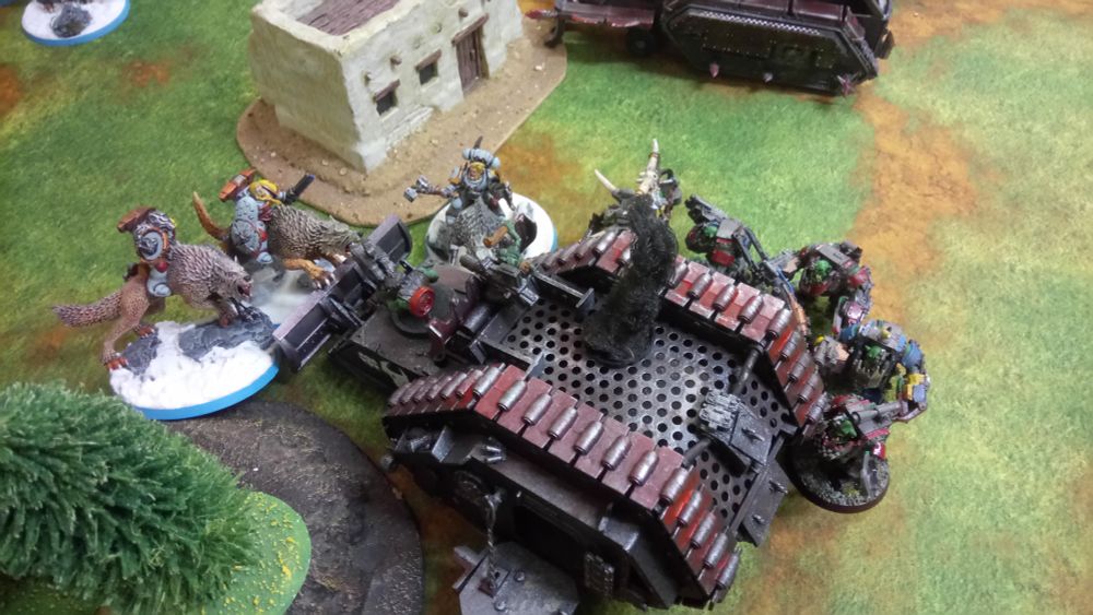 A Konverted Rogue Trader era Land raider burns after an encounter with Space Wolf cavalry. A mega armoured  warboss and mega armoured retinue have bailed out and are about to charge the doggies.