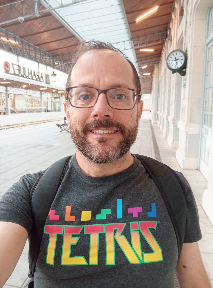 Hombre sonriente con una camiseta de Tetris en la estación de tren de Aranjuez (Madrid)