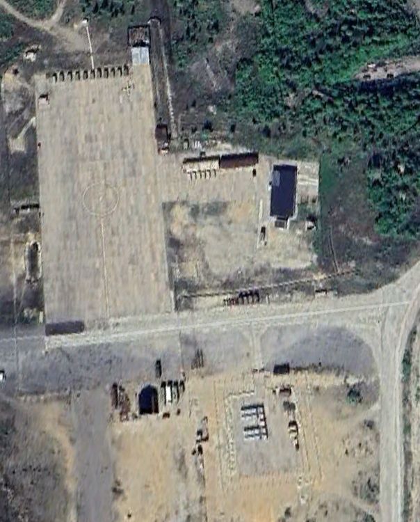 Screenshot form Google Earth, summer 2023. The construction of a new, fenced pad is finished, and four white containers are placed on it. In the upper right corner of the large pad in the top part of the picture the outline of a Forpost UAV can be seen. 
