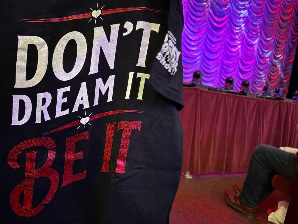 Don't Dream it Be it shirt in front of an empty stage.
