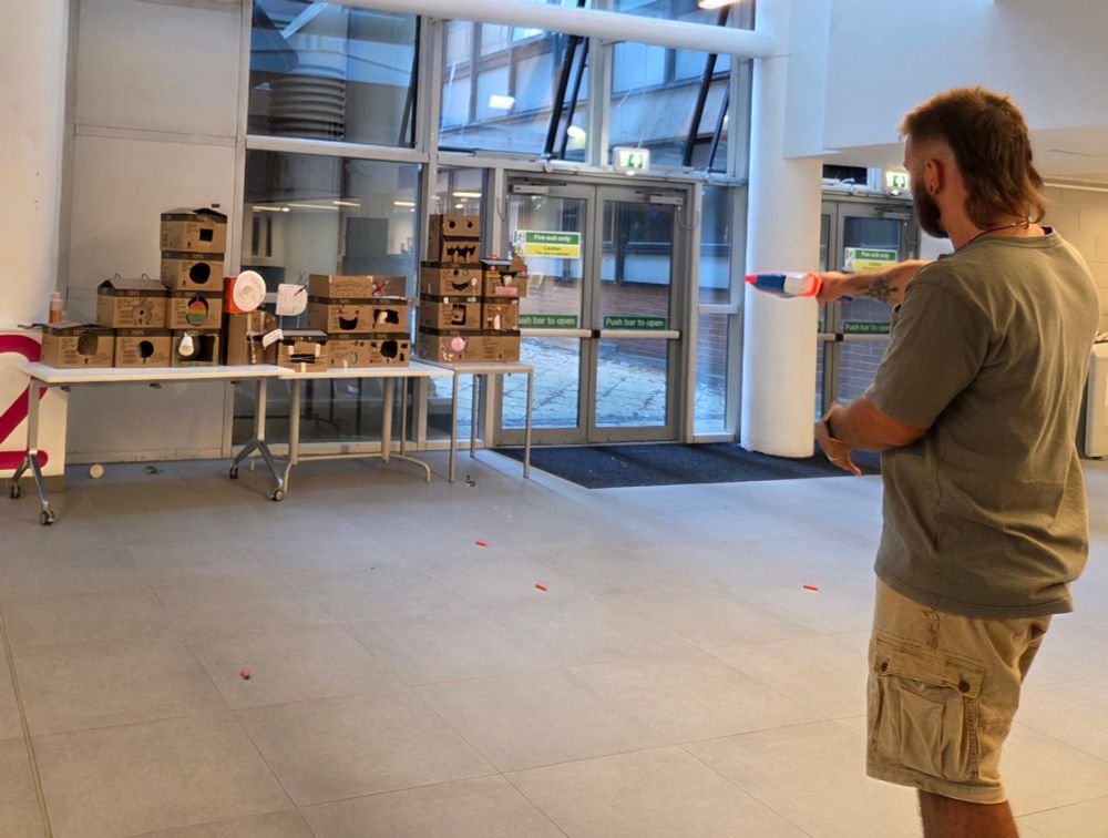 Shooting range made of boxes with someone aiming a nerfgun at one of the targets.