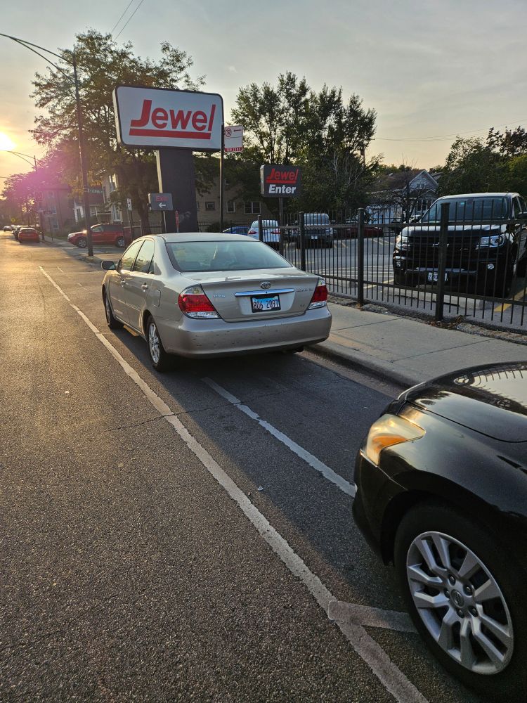 Drivers illegally parked in a bike lane even though there is a parking lot right there