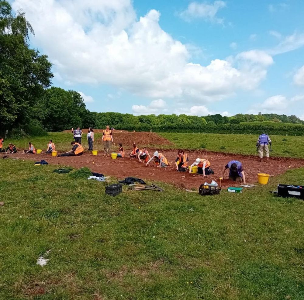A group of people excavating a large area in a green field