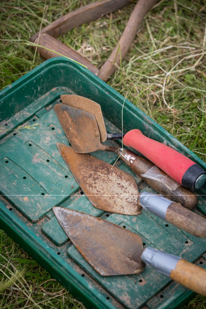 Archaeology trowels in a green tray on grass