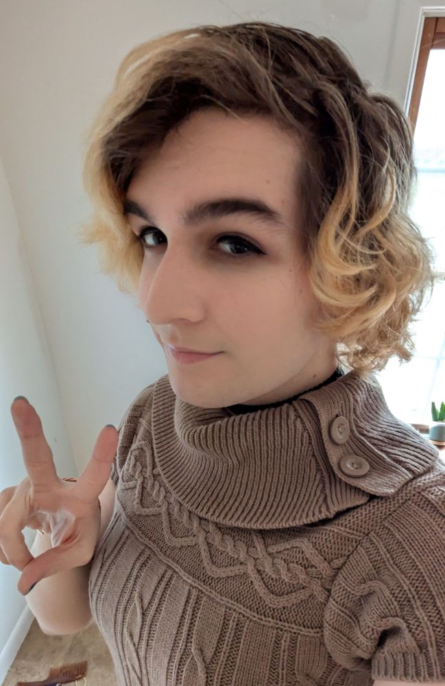 Girl taking a selfie wearing a short sleeved sweater flashing a peace sign