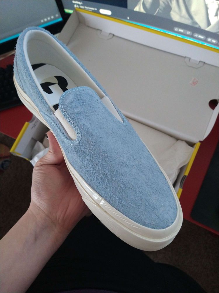 A light blue colored Golf Wang x Converse slip-on shoe being unboxed.