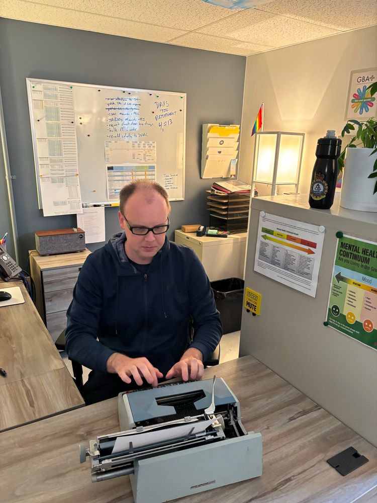 Man sitting at a desk with a typewriter. 