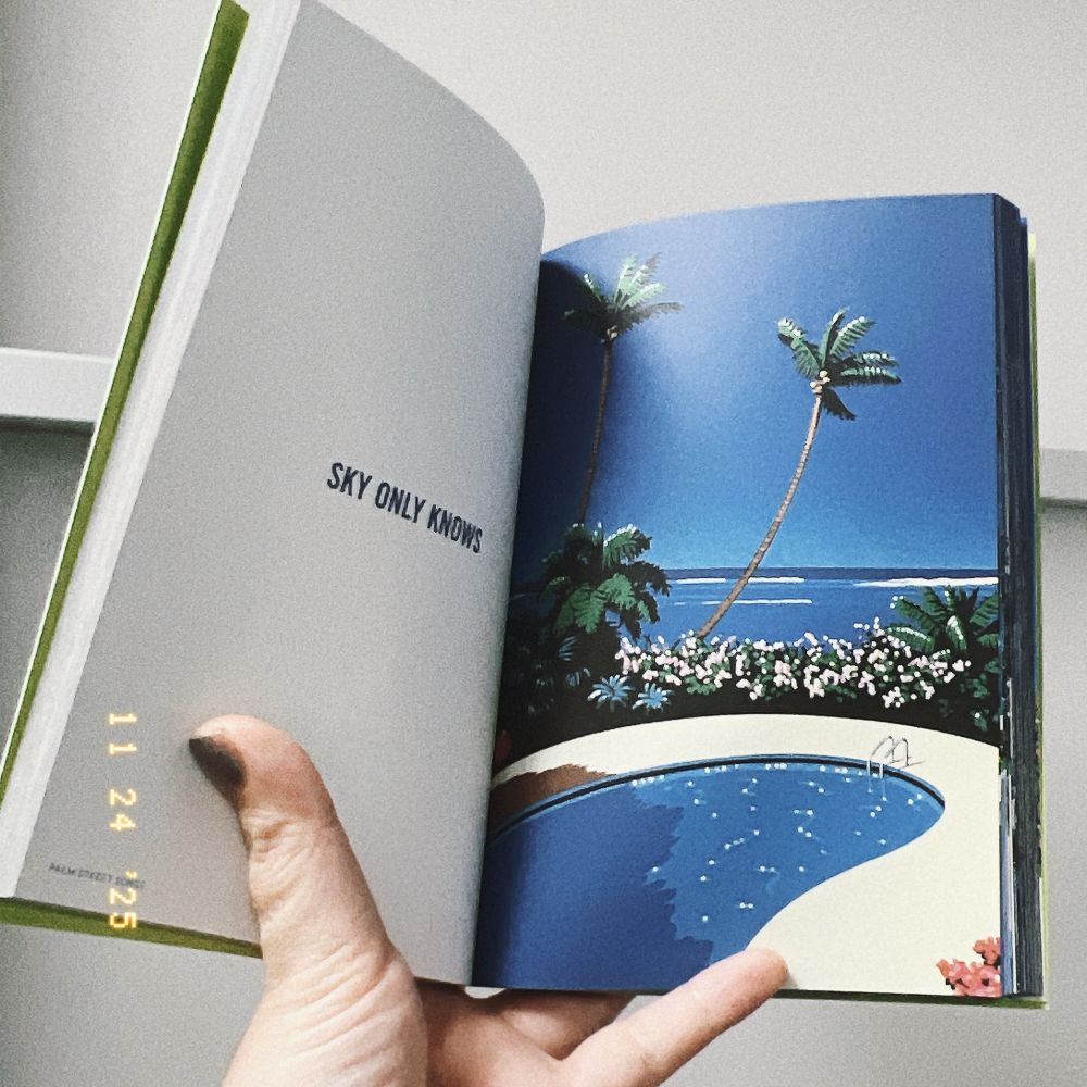 永井博作品集『Palm Street Songs』の中を見せる形で手に持った写真。夏のプールサイドのイラストが見開きの右ページに描かれ、左ページには「SKY ONLY KNOWS」というテキストが書かれている。