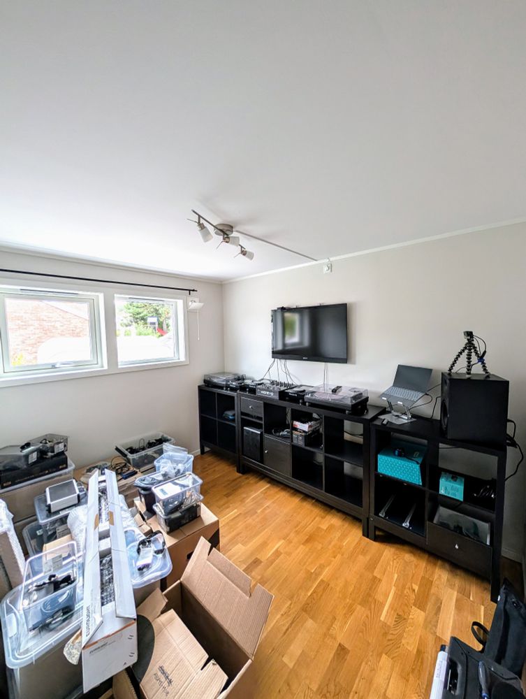 A room with a dj setup and a lot of unpacked boxes