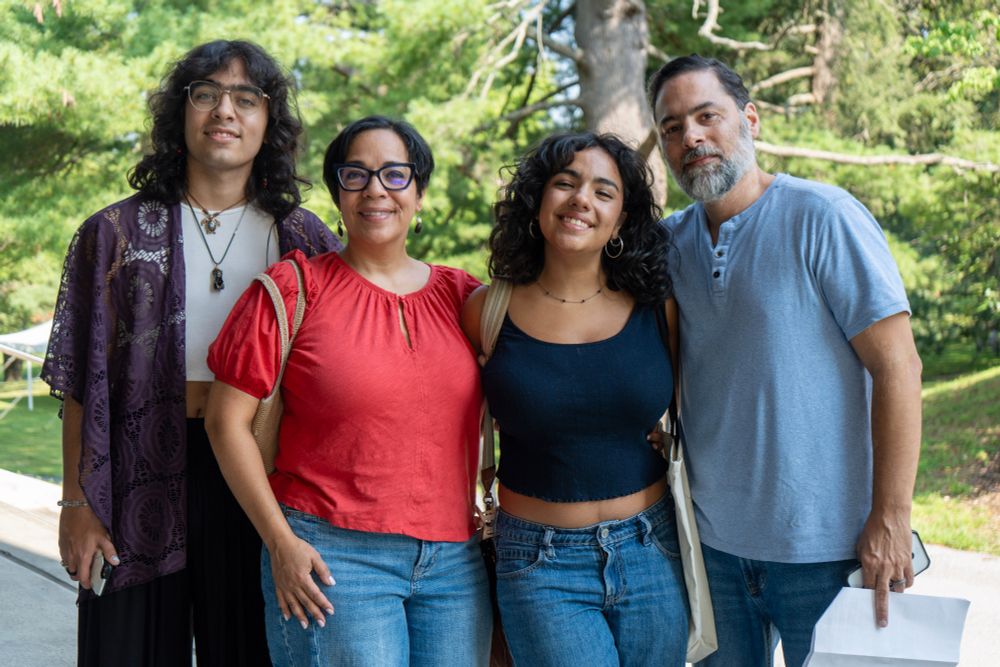 A family poses for a group photo in front of a large tree.