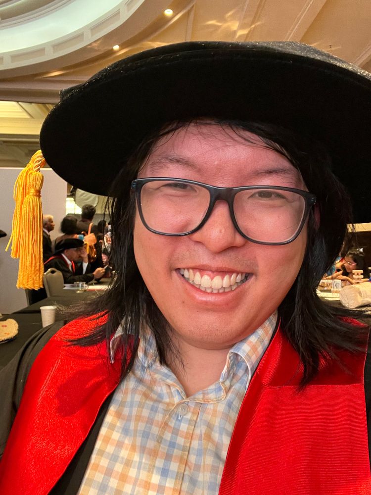 A person (he/him) wearing academic robes and a floppy hat with tassels. 