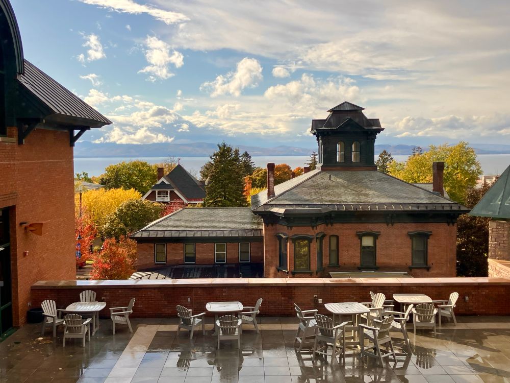 View of Victorian-style buildings with lake and mountains in background and slate terrace in foreground