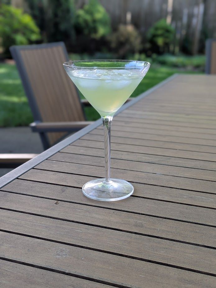 Photo of a martini glass with a vaguely green drink -- a "Last Word" containing equal parts Gin, Green Chartreuse, Maraschino and Lime -- along with the ice cubes from shaking it up.