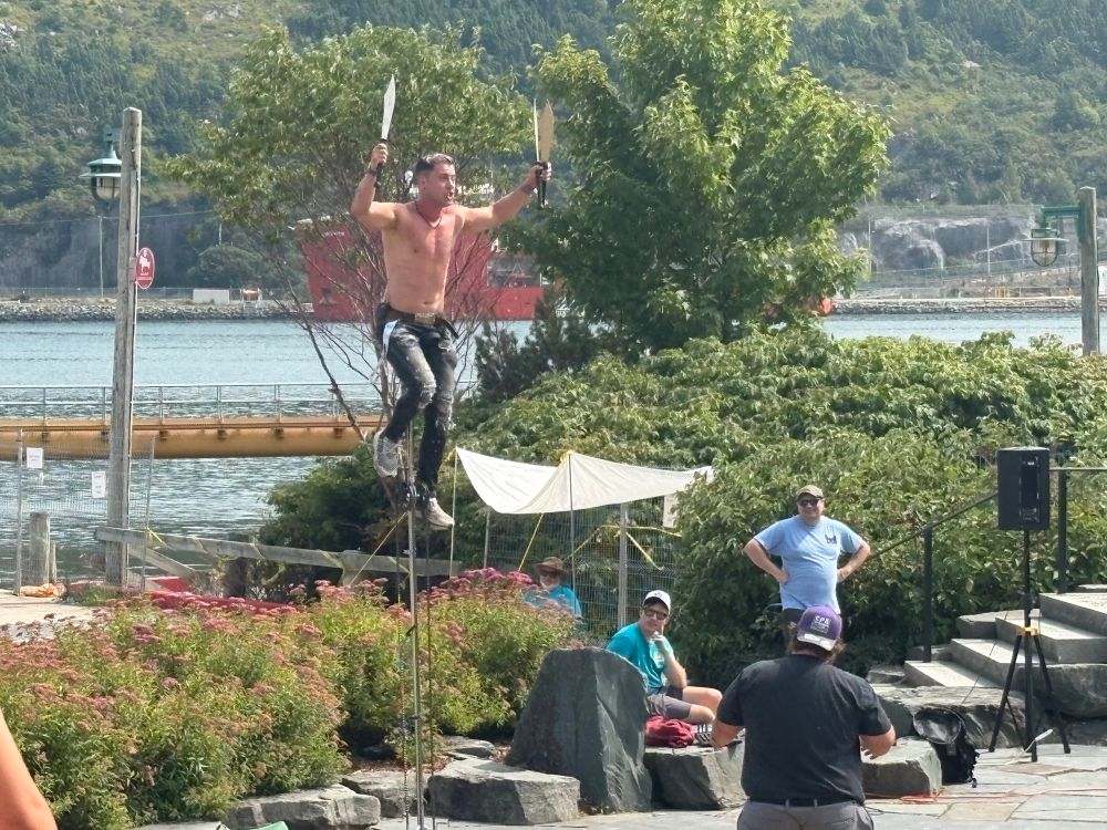 The Mighty Quinn but shirtless on a unicycle with knives 