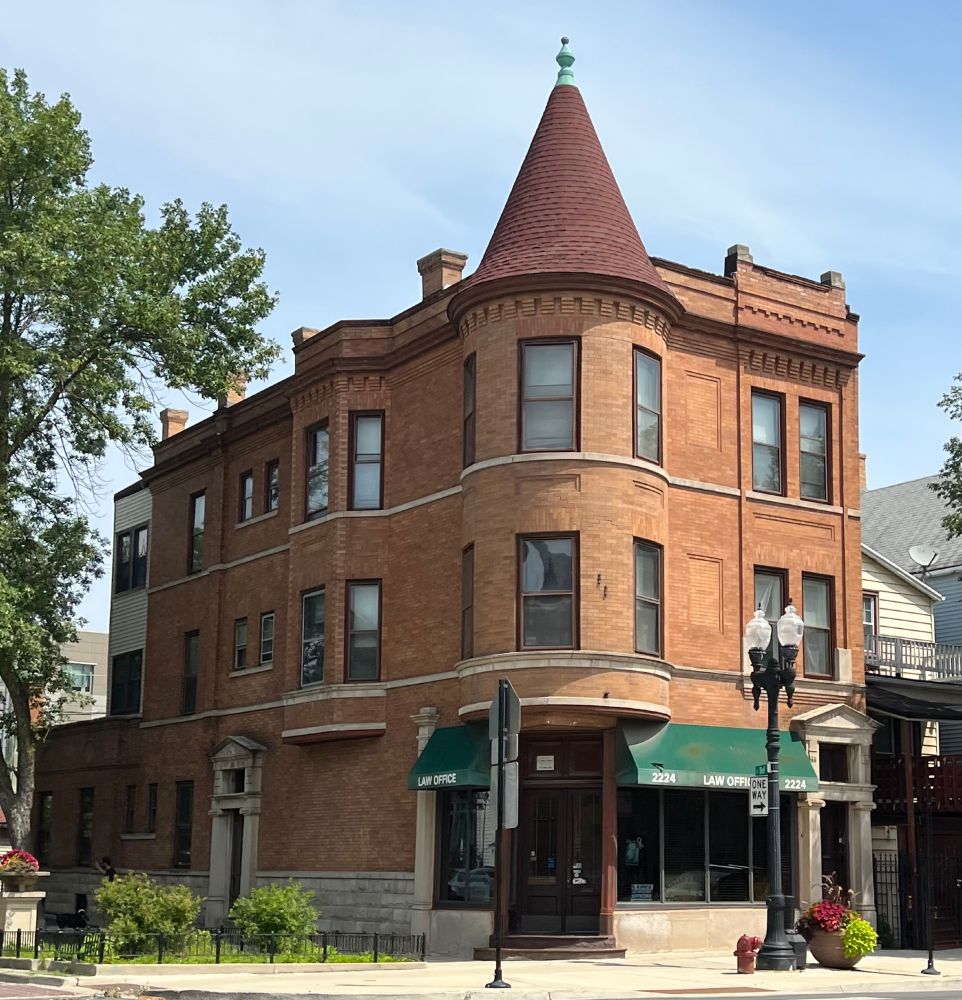 Built ca. 1904, John K. Neebe, architect. Three-story orange brick corner building with brick turret on the corner of the 2nd and 3rd floors. The turret has a witches' hat roof. There is stone trim around two entrances, although not around the main entrance at the corner. 